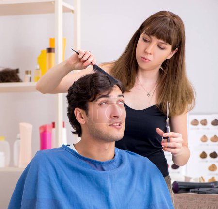 Téléchargez les photos : Les jeunes attirent l'homme visitant le coiffeur féminin - en image libre de droit