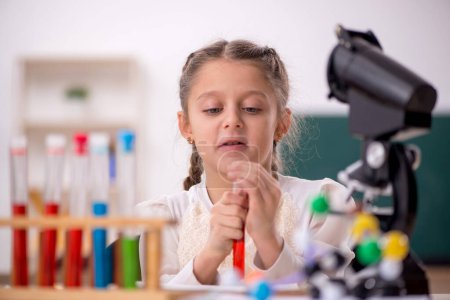 Téléchargez les photos : Little girl studying chemistry in the classroom - en image libre de droit
