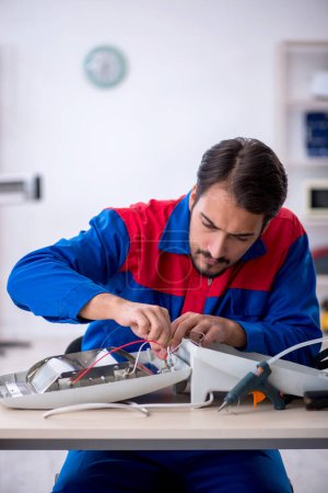 Photo for Young repairman repairing heater at workshop - Royalty Free Image