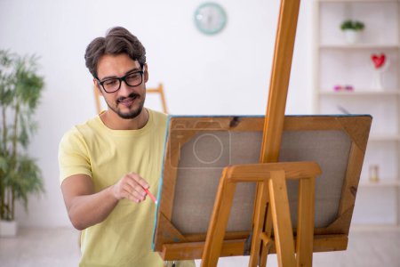 Foto de Joven pintor masculino disfrutando de la pintura en casa - Imagen libre de derechos