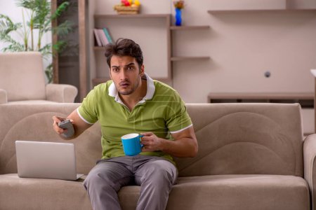 Photo for Young male student watching tv at home - Royalty Free Image