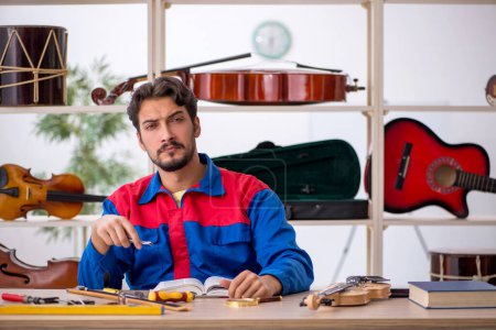 Photo for Young man repairing musical instruments indoors - Royalty Free Image