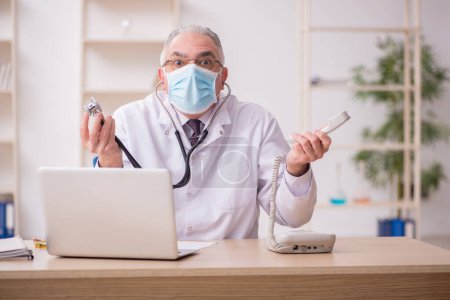 Photo for Old doctor working in the clinic during pandemic - Royalty Free Image