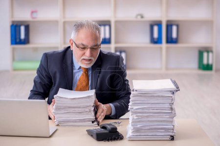 Foto de Old male employee and too much work at workplace - Imagen libre de derechos