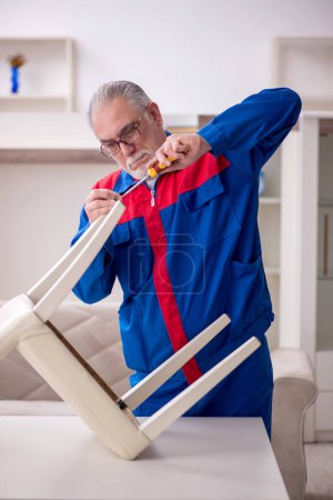 Téléchargez les photos : Old repairman repairing chair at home - en image libre de droit