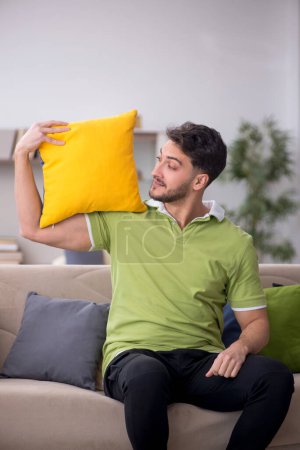 Téléchargez les photos : Jeune homme avec beaucoup d'oreillers à la maison - en image libre de droit