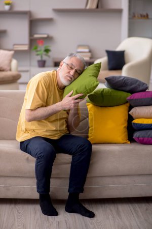 Téléchargez les photos : Homme âgé avec de nombreux oreillers à la maison - en image libre de droit