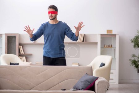 Photo for Blindfolded young man seeking at home - Royalty Free Image