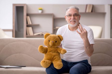 Téléchargez les photos : Vieil homme avec ours jouet à la maison - en image libre de droit