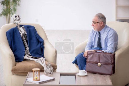 Foto de Viejo jefe y esqueleto masculino en concepto de reunión de negocios - Imagen libre de derechos