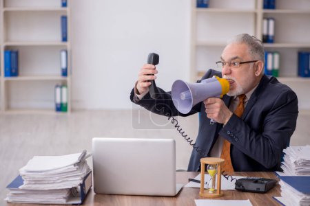 Photo for Old employee holding megaphone at workplace - Royalty Free Image