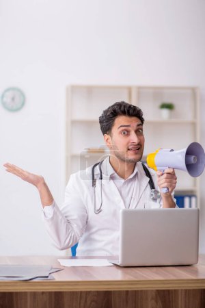 Photo for Young doctor holding megaphone in the clinic - Royalty Free Image