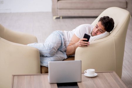 Téléchargez les photos : Jeune homme paresseux commençant la journée à la maison - en image libre de droit