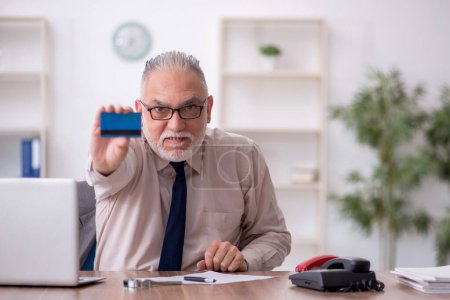 Téléchargez les photos : Ancien employé titulaire d'une carte de crédit sur le lieu de travail - en image libre de droit