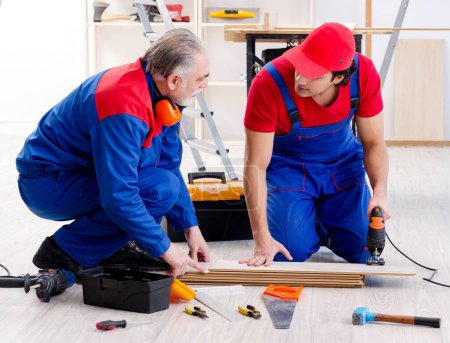 Photo for The two professional contractors laying flooring at home - Royalty Free Image
