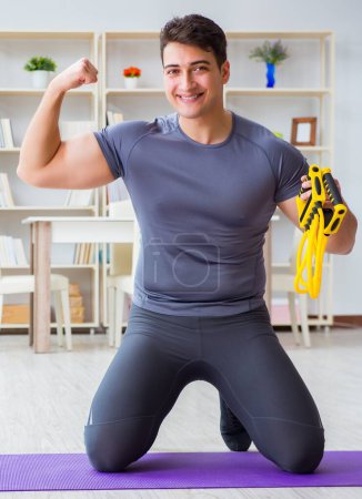 Foto de Hombre joven haciendo ejercicio en casa en el deporte y el concepto de estilo de vida saludable - Imagen libre de derechos