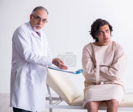 Téléchargez les photos : Le médecin psychiatre homme âgé examinant le jeune patient - en image libre de droit