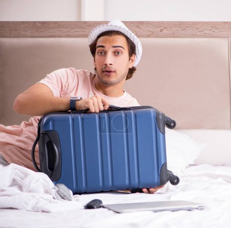 Téléchargez les photos : L'homme avec valise dans la chambre à coucher attendant le voyage - en image libre de droit
