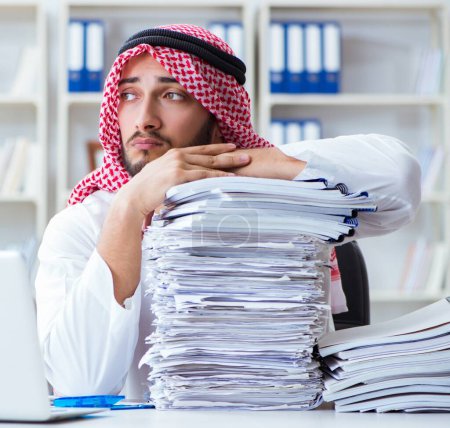 Photo for Arab businessman working in the office doing paperwork with a pile of papers - Royalty Free Image