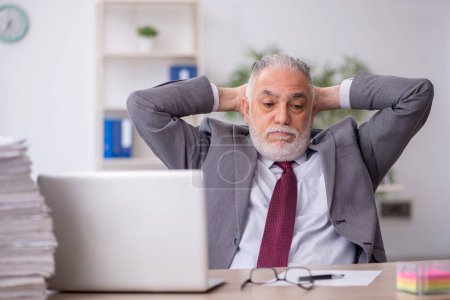 Photo for Old employee unhappy with excessive work at workplace - Royalty Free Image