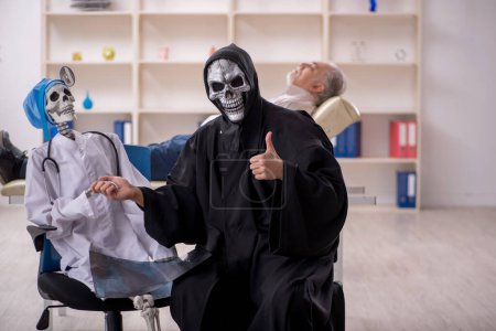 Foto de Dos doctores del diablo examinando paciente viejo - Imagen libre de derechos