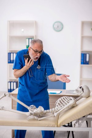 Photo for Old doctor examining skeleton at the hospital - Royalty Free Image