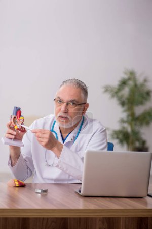 Téléchargez les photos : Vieux médecin cardiologue travaillant à la clinique - en image libre de droit