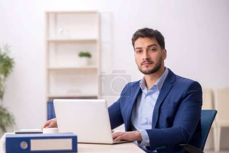 Photo for Young employee sitting at workplace - Royalty Free Image