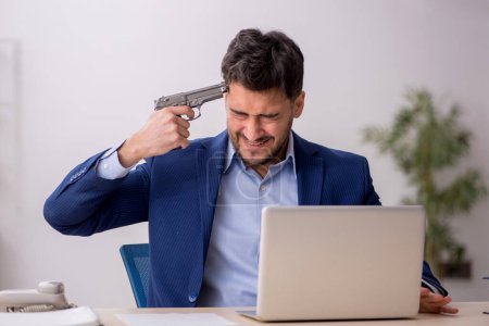 Photo for Young employee holding gun at workplace - Royalty Free Image