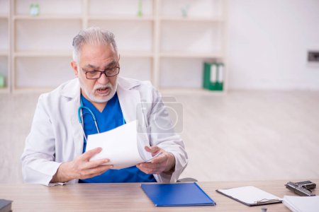 Photo for Old male doctor working at the hospital - Royalty Free Image