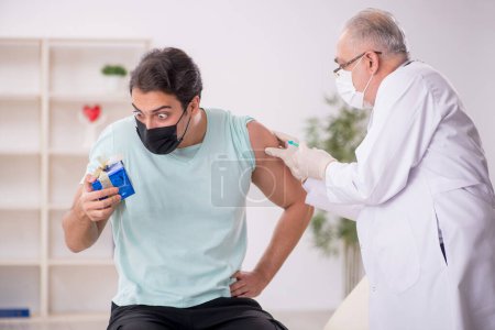 Photo for Old male doctor giving giftbox to young patient - Royalty Free Image