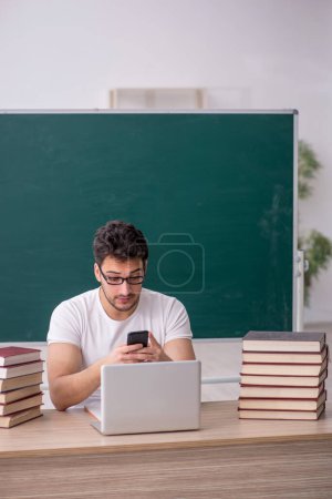 Téléchargez les photos : Jeune étudiant assis dans la salle de classe - en image libre de droit