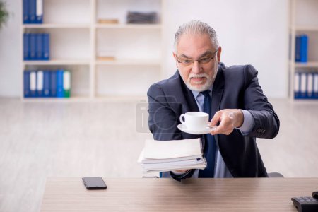 Photo for Old employee drinking tea at workplace - Royalty Free Image