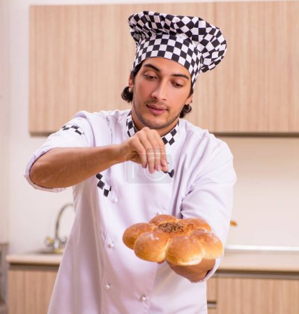Téléchargez les photos : Le jeune boulanger masculin travaillant dans la cuisine - en image libre de droit