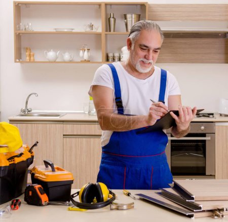 Téléchargez les photos : L'entrepreneur âgé réparateur travaillant dans la cuisine - en image libre de droit