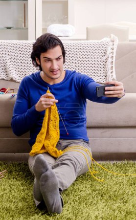 Photo for The young good looking man knitting at home - Royalty Free Image