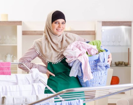 Photo for The woman in hijab doing clothing ironing at home - Royalty Free Image