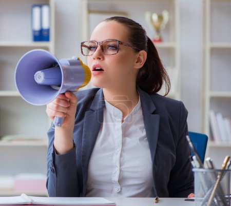 Foto de La mujer de negocios enojada gritando con un altavoz en la oficina - Imagen libre de derechos