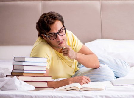 Photo for The young student studying in bed for exams - Royalty Free Image