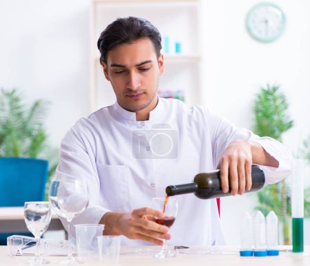 Foto de El químico masculino examinando muestras de vino en el laboratorio - Imagen libre de derechos