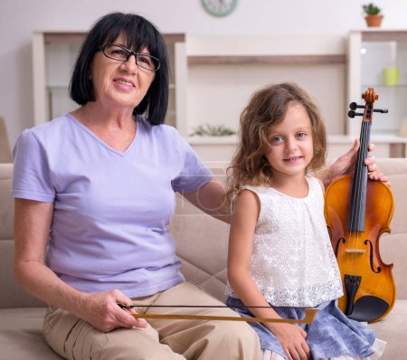 Téléchargez les photos : La vieille dame enseignant à la petite fille à jouer du violon - en image libre de droit