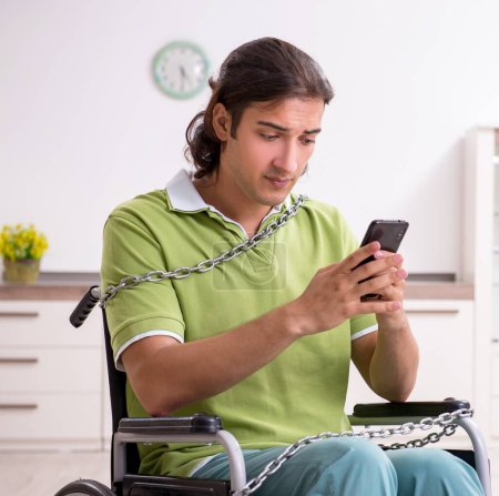 Foto de El joven hombre inválido en silla de ruedas sufriendo en casa - Imagen libre de derechos