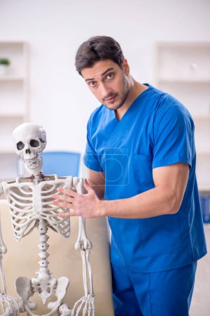 Foto de Joven doctor y paciente esqueleto en la clínica - Imagen libre de derechos