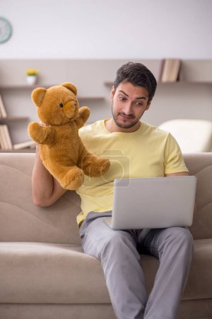 Photo for Young male student hugging toy bear at home - Royalty Free Image