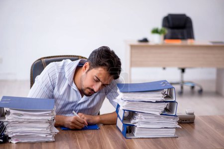 Photo for Young businessman employee unhappy with excessive work at workplace - Royalty Free Image
