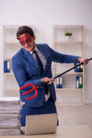 Photo for Devil businessman unhappy with excessive work at workplace - Royalty Free Image