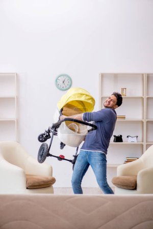 Téléchargez les photos : Jeune entrepreneur masculin s'occupant du nouveau-né à la maison - en image libre de droit