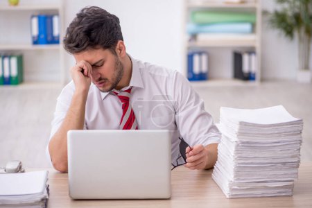 Photo for Young employee unhappy with excessive work in the office - Royalty Free Image