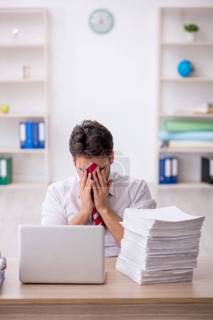 Foto de Joven empleado descontento con el exceso de trabajo en la oficina - Imagen libre de derechos