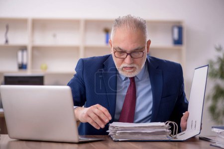 Téléchargez les photos : Ancien employé travaillant dans le bureau - en image libre de droit